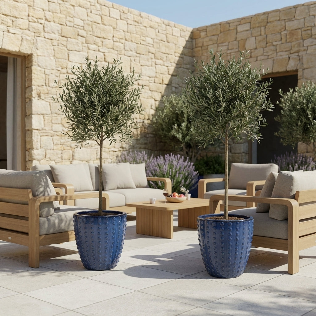 Detail na ručně vyráběný keramický květináč Attila Anticky modrá z terakoty s lesklou glazurou a reliéfem na slunné kamenné dlažbě.