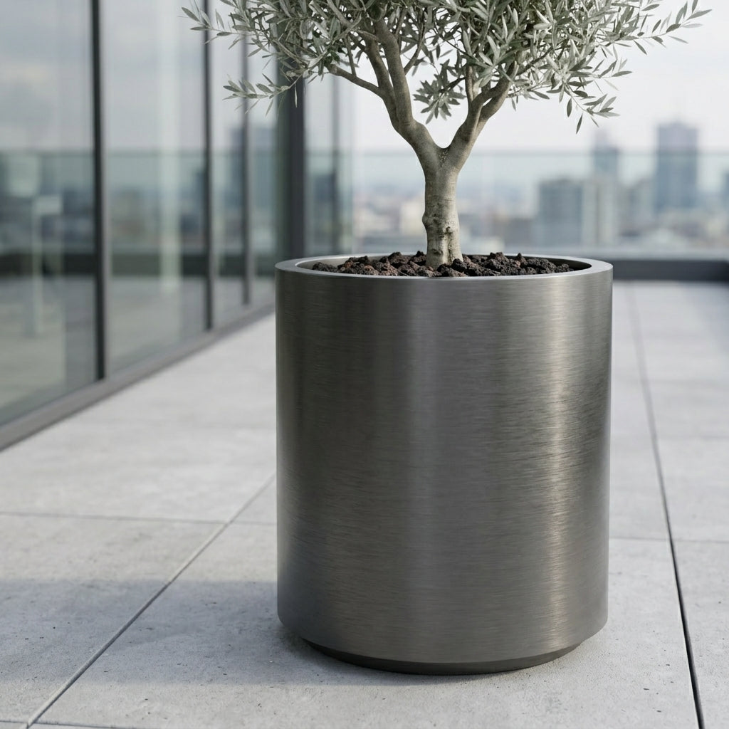 Detail na velký květináč z nerezové oceli Metropole v matně černé barvě s olivovníkem na moderní městské terase.