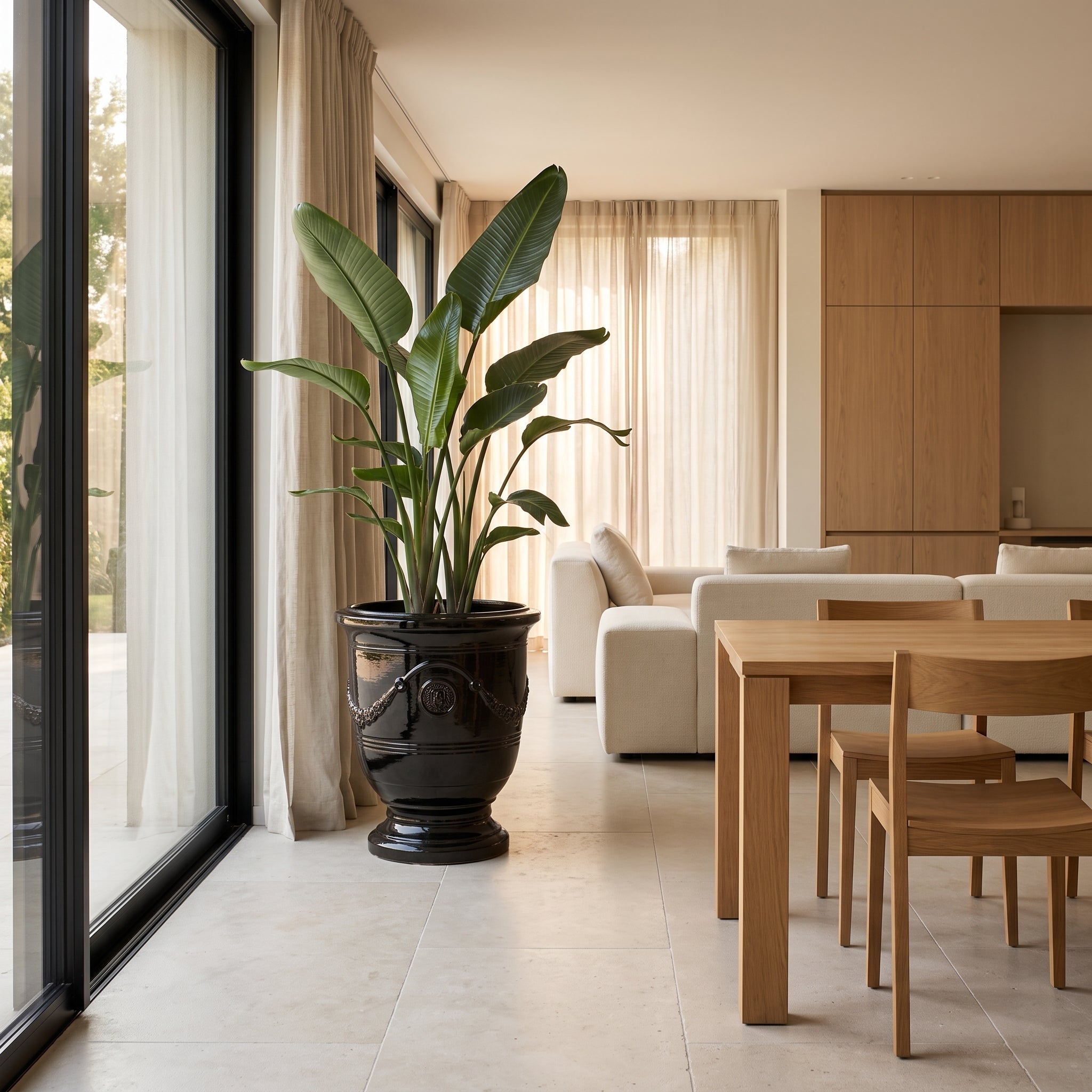 Keramický květináč RICHELIEU - Černý - XXL (58 x 70 cm) se strelícií v prosvětleném luxusním moderním interiéru.